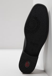 Semelle de chaussure noire avec finition texturée, présentant un logo circulaire et le mot "Pugatti". La taille 42 est embossée sur le côté.