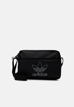 Bolso bandolera rectangular negro con correa ajustable, bolsillo delantero con cremallera y logo trefoil de Adidas en blanco junto con texto en el panel frontal.
