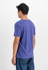 Lilla lühikeste varrukatega T-särk ümmarguse kaelusega, lõdva istuvuse ja pehme puuvillase tekstuuriga. Silmatorkav õmblusdetail varrukatel ja kaeluses.