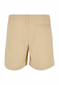 Béžové plavky s elastickým pásom, jedným vreckom na zips na zadnej strane a hladkým, ľahkým materiálom. Klasický strih a jednoduchý dizajn.