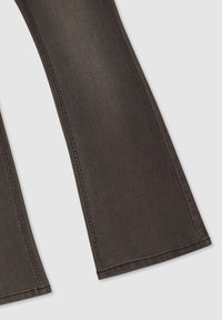Pantaloni in denim nero a campana con una texture liscia, caratterizzati da cuciture laterali evidenti e un'ampia apertura della gamba nella parte inferiore.