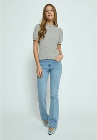 Striped, fitted short-sleeve top with a round neckline and puff sleeves, paired with light blue flared jeans and decorative silver shoes.