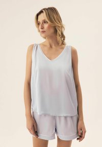 Jasnoniebieska satynowa koszulka na ramiączkach z dekoltem w serek i bez rękawów, połączona z dopasowanymi szortami z założonym paskiem i miękką teksturą.