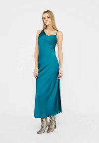 Sukienka na ramiączkach z satyny w kolorze morskim, z dopasowanym stanikiem i bocznym rozcięciem. Połączona z metalicznymi botkami na koturnie w wzór wężowy.