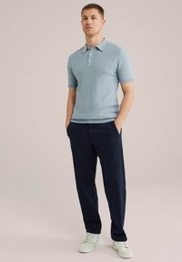 Svetlo modra teksturirana polo majica s kratkimi rokavi, v kombinaciji s temno mornarskimi hlačami in belimi supergami. Standardna prileganje z klasičnim ovratnikom.