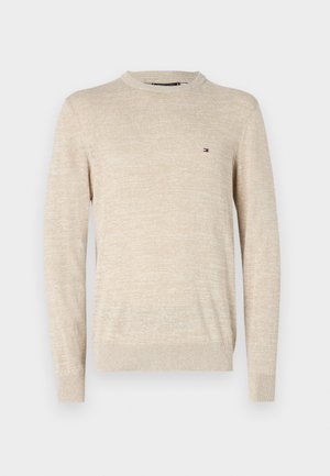 Suéter de punto beige con cuello redondo, mangas largas y un pequeño logotipo bordado en el pecho. Textura suave con un patrón jaspeado.