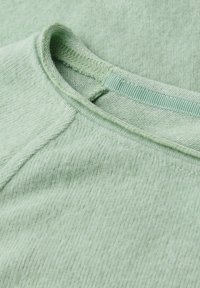 T-shirt verde chiaro con una trama a coste, caratterizzato da un collo rotondo e dettagli cuciti. Tessuto morbido con una finitura liscia.