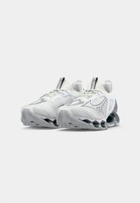 White athletic shoes with mesh upper, textured patterns, and a cushioned sole featuring black and grey accents. Laced design and padded collar.