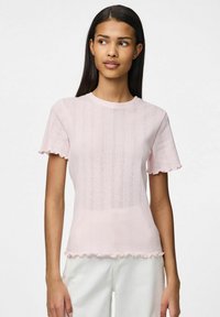 Jasnoróżowa bluzka z krótkim rękawem wykonana z teksturowanej tkaniny, z żebrowanym wzorem, falbaniastymi krawędziami i okrągłym dekoltem.