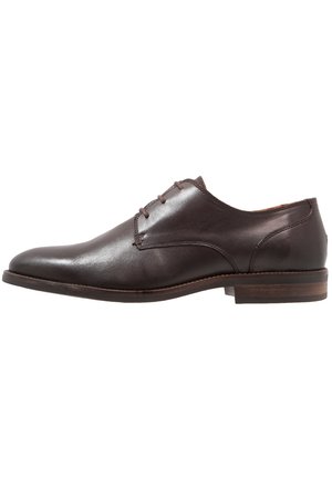Zapato de vestir para hombre de cuero marrón oscuro con cordones cerrados y un tacón bajo de madera apilada, mostrado de perfil sobre fondo blanco.