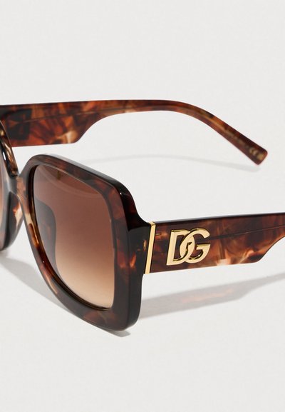 Καφέ γυαλιά ηλίου με μοτίβο χελώνας, μεγάλα τετράγωνα πλαίσια, καφέ φακούς με διαβάθμιση και χρυσά λογότυπα στα πλαϊνά.