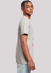 Graues Baumwoll-T-Shirt mit Rundhalsausschnitt, kurzen Ärmeln und einem pinken Frontdesign, präsentiert in einer figurbetonten Silhouette.