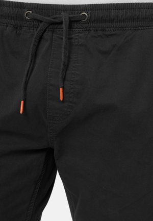 Pantalones cortos negros con cintura elástica, presentan un cordón con puntas naranjas, confeccionados en una tela lisa. Incluye costuras laterales para mayor estructura.