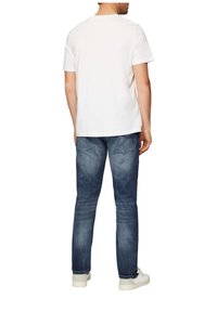 Witte katoenen T-shirt met korte mouwen, ronde halslijn, gecombineerd met blauwe spijkerbroek. Sneakers in een lichte kleur maken de outfit compleet.