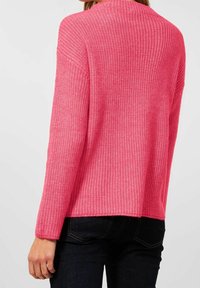 Överdimensionerad, ribbad tröja i klar rosa, med hög krage och långa ärmar, tillverkad av ett mjukt stickat material.