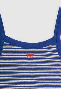 Mėlynų dryžių tankų marškiniai su briaunota tekstūra, plačiomis petnešėlėmis ir raudona Levi's ženklo etikete priekyje. Dryžių spalvos - balta ir juoda.