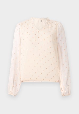 Blouse saumon clair avec décolleté en V, manches bouffantes transparentes et petit motif à pois métalliques. Tissu doux avec des poignets élastiques froncés.