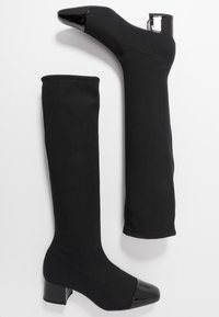Knielange schwarze Stretch-Stoffstiefel mit glänzendem schwarzen Blockabsatz und Zehenkappe, die ein schlankes, eng anliegendes Design aufweisen.