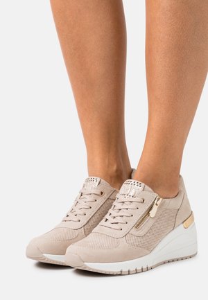 Beige Keil-Sneaker mit strukturiertem Obermaterial, Mesh-Einsätzen und einem metallischen Reißverschluss. Verfügt über eine weiße Sohle und dekorative Perforationen.