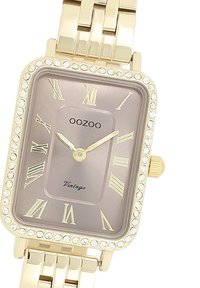 Montre rectangulaire couleur or avec un cadran marron texturé, des chiffres romains, des accents en cristal sur la lunette et un bracelet en maillons métalliques.