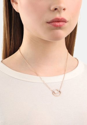 Roségoldene Halskette mit miteinander verwobenen runden Anhängern, die eine glatte Oberfläche und kleine klare Akzente aufweisen, getragen zu einem hellen Hemd.
