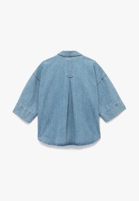 Denimskjorte i lys blå farve, afslappet pasform, oversized ærmer, rygfold detalje og syede kanter langs kraven og manchetterne.