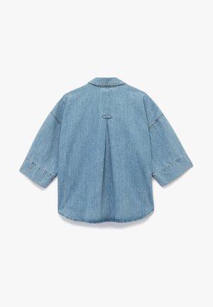 Camisa de denim de color azul claro, ajuste relajado, mangas amplias, detalle de pliegue en la parte posterior y borde cosido alrededor del cuello y los puños.