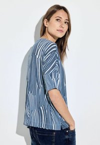 Blauw-wit geblokt kortemouwenshirt met een comfortabele pasvorm en een ronde halslijn. Zachte stof met abstracte strepen en vormen.
