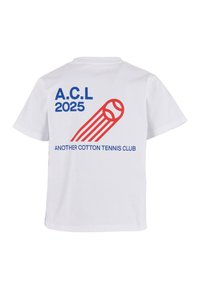 Baltas kokvilnas T-krekls ar zilu tekstu "A.C.L 2025" un "ANOTHER COTTON TENNIS CLUB." Sarkanā grafika ar tenisa bumbu un kustības līnijām.