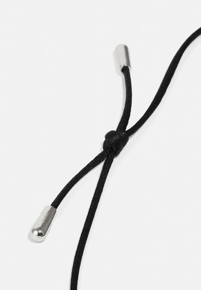 Cordon noir avec un nœud au centre, doté d'accents métalliques aux extrémités. La texture est lisse avec une apparence tressée.