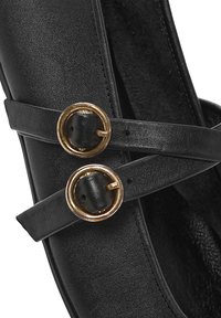 Scarpa flat nera realizzata in pelle liscia con cinturini incrociati neri e due fibbie circolari in tonalità oro. L'interno ha una finitura testurizzata.
