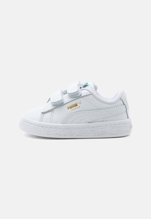 Baskets basses blanches avec deux brides Velcro, semelle texturée et logo doré Puma Suede sur le côté.