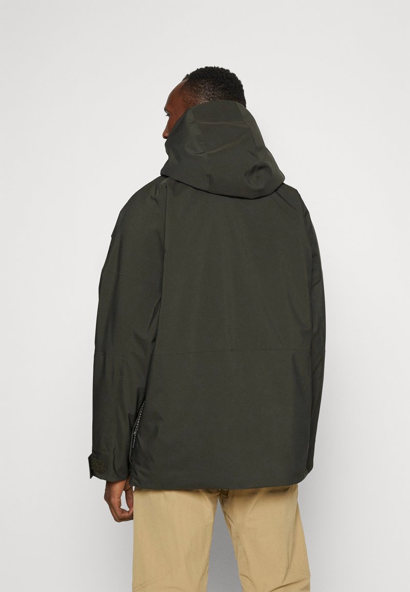 Chaqueta con capucha de un verde oscuro y corte relajado, con una textura suave y un cordón ajustable en la capucha. Vista trasera.