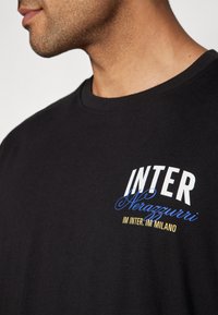 Svart bomull T-skjorte med hvit og blå trykt tekst "INTER Nerazzurri" med gule aksenter, rund hals og korte ermer.