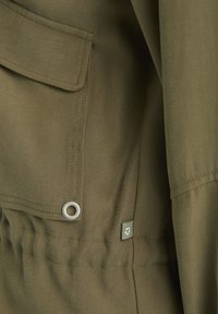 Olivegrüner Utility-Jacke mit einer Vorderseite Tasche, elastischem Bund, strapazierfähigem Material, metallischen Ösen und einem dezenten Logo-Patch.