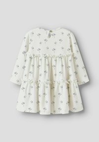 Robe blanche avec petits imprimés floraux bleus, manches longues, volants à deux niveaux et fermeture par boutons au niveau de la nuque. Texture de tissu douce.
