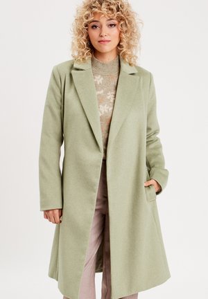Manteau en laine vert clair avec revers à cran, manches longues et poches latérales. Il arrive à mi-cuisse et présente une silhouette épurée et ajustée.
