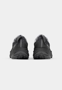 Chaussures de sport noires avec une tige texturée grise, présentant des accents réfléchissants et une semelle en caoutchouc robuste pour une meilleure adhérence.