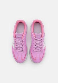 Růžové sportovní boty s texturovaným povrchem, bílými pruhy a ladícími šněrovadly. Mají polstrovaný límec a jazyk v světle růžové barvě.