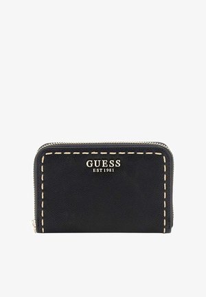 Portefeuille en cuir noir avec surpiqûres beiges et fermeture éclair argentée, estampillé "GUESS EST 1981" en lettres argentées sur le devant.