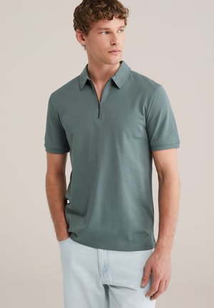 Polo met korte mouwen in een gemêleerde teal stof, voorzien van een ritskraag en een slanke pasvorm. Getextureerde details aan de zoom en zijnaden.