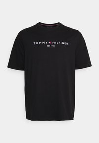 Mustat puuvillapaita pyöreällä kaula-aukolla. Siinä on valkoinen teksti "TOMMY HILFIGER EST. 1985" ja pieni punainen ja sininen logotunnus.