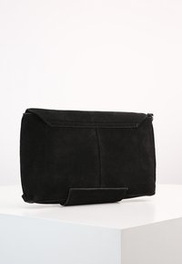 Černá semišová kabelka s překládaným klopou, obdélníkového tvaru, hladké textury, s minimalistickým designem a bez viditelného kování.