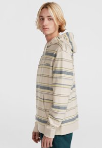 Sudadera con rayas beige que presenta rayas amarillas y azules, un bolsillo delantero, capucha ajustable con cordón y logo bordado en el pecho.