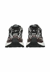Schwarz-weiße Sneakers mit einem Zebra-Streifenmuster, verziert mit silbernen Nieten auf einem kastanienbraunen Akzent und einer strukturierten schwarzen Gummisohle.