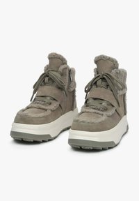 Grijze hoge sneakers met pluizige accenten, gemaakt van suède, en met gestructureerde veters. Voorzien van een dikke witte zool en een sluiting met rits aan de zijkant.