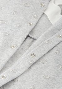 Cárdigan gris de tela suave, con botones a presión plateados y un sutil patrón de pequeños motivos. Diseño texturizado, cálido y ligero.