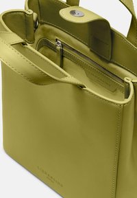 Torebka Liebeskind w intensywnym limonkowym skórze o gładkiej fakturze, z zamykaną na zamek kieszenią, górnym zapięciem na klapkę oraz podwójnymi uchwytami.