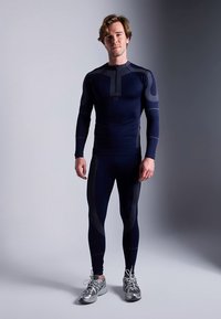 Roupa desportiva azul-marinho com mangas compridas e leggings com detalhes texturizados. Feita de material elástico, projetada para movimento ativo.