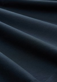 Dark navy fabric, smooth texture, with gentle waves and folds. Uniform color, no visible patterns or accents. Soft to the touch.